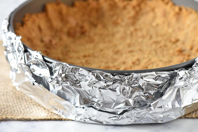 foil wrapped springform pan with graham cracker crust