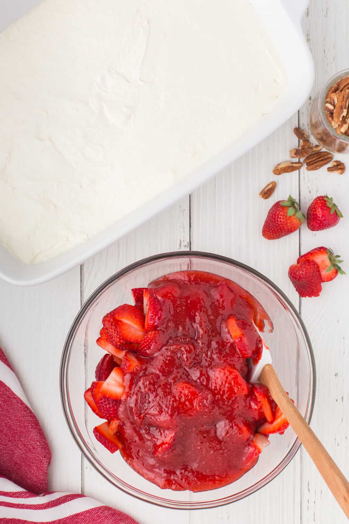 mixing fresh strawberries with a homemade strawberry sauce to make the strawberry topping layer for strawberry delight no bake dessert