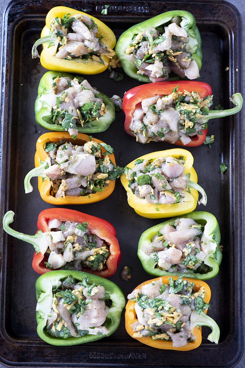 stuffing bell peppers with chicken mixture on a baking sheet