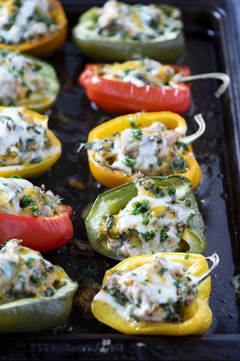 baked low carb stuffed peppers with chicken on baking sheet, sprinkled with parsley over melted cheese