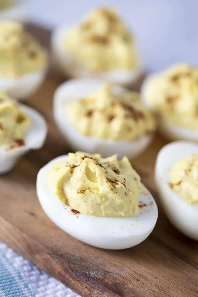 easy deviled eggs sprinkled with paprika on a wooden cutting board