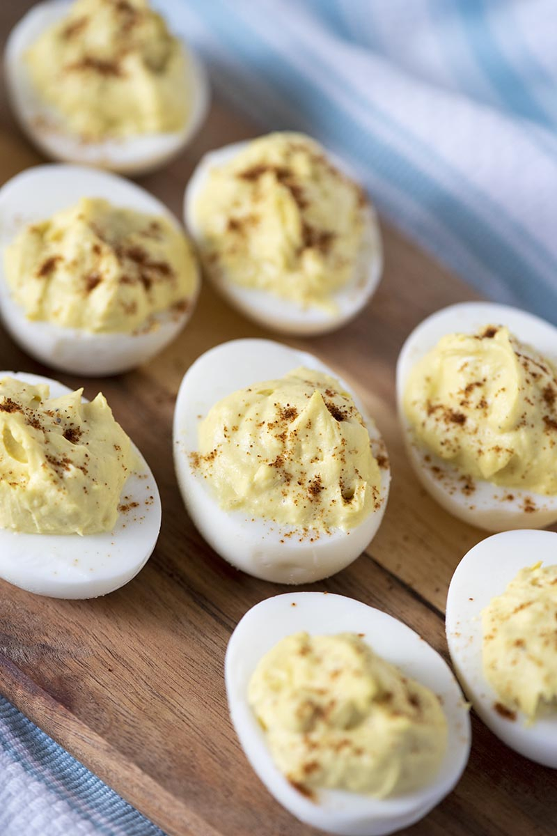 making deviled eggs with a sprinkle of paprika on a wooden cutting board