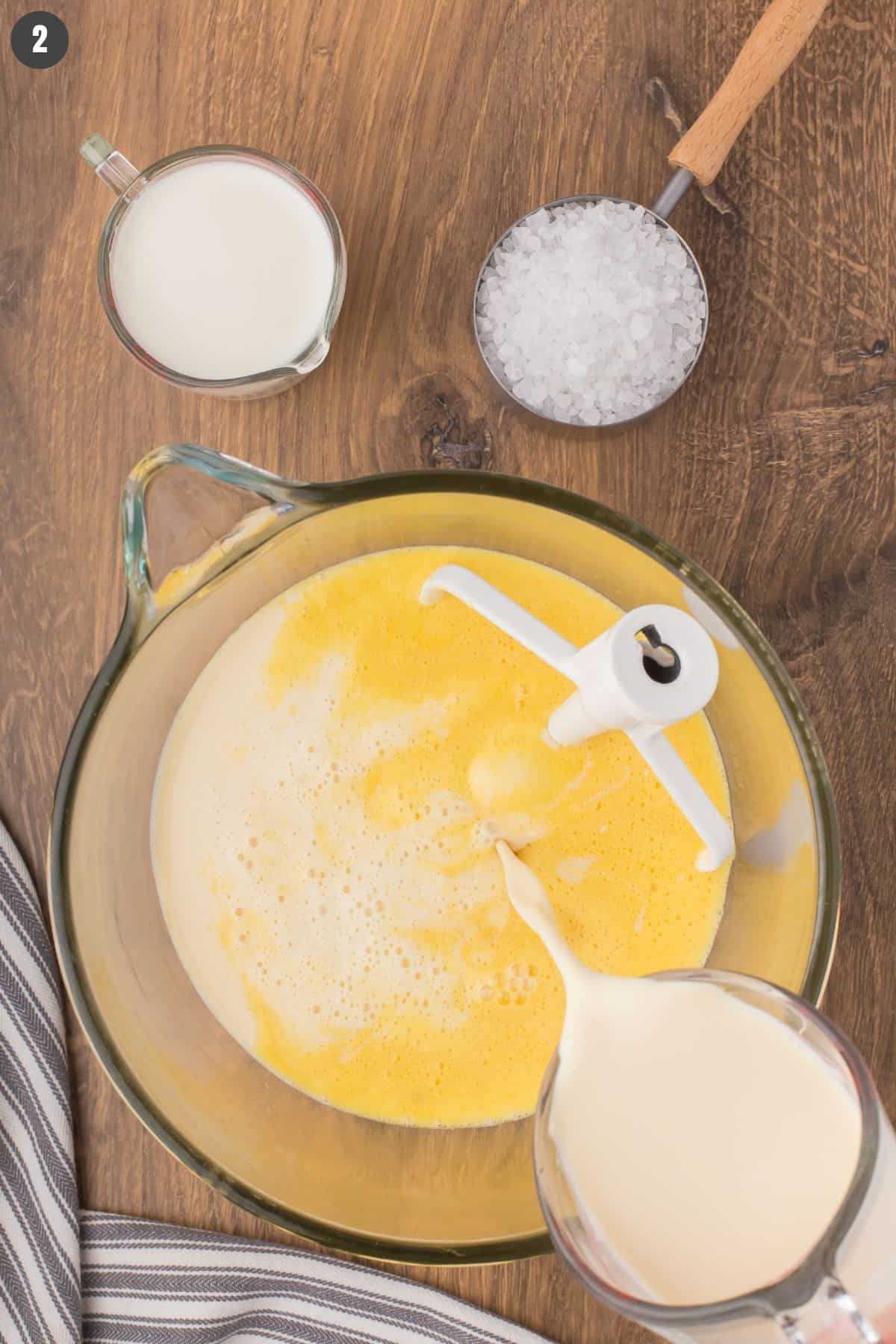pouring evaporated milk into the egg custard mixture to make old fashioned homemade vanilla ice cream