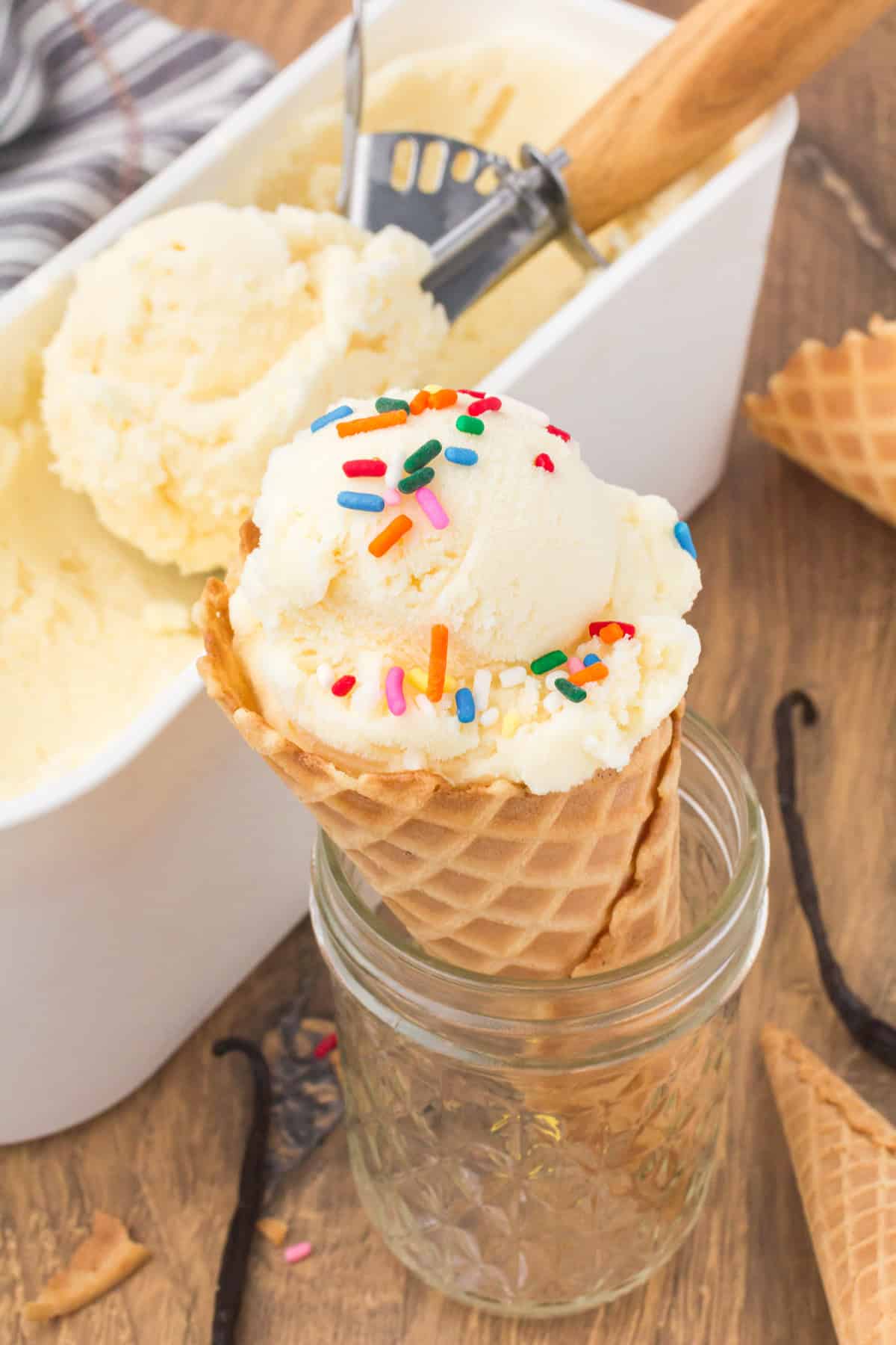 homemade vanilla ice cream scooped into a waffle cone with sprinkles on top