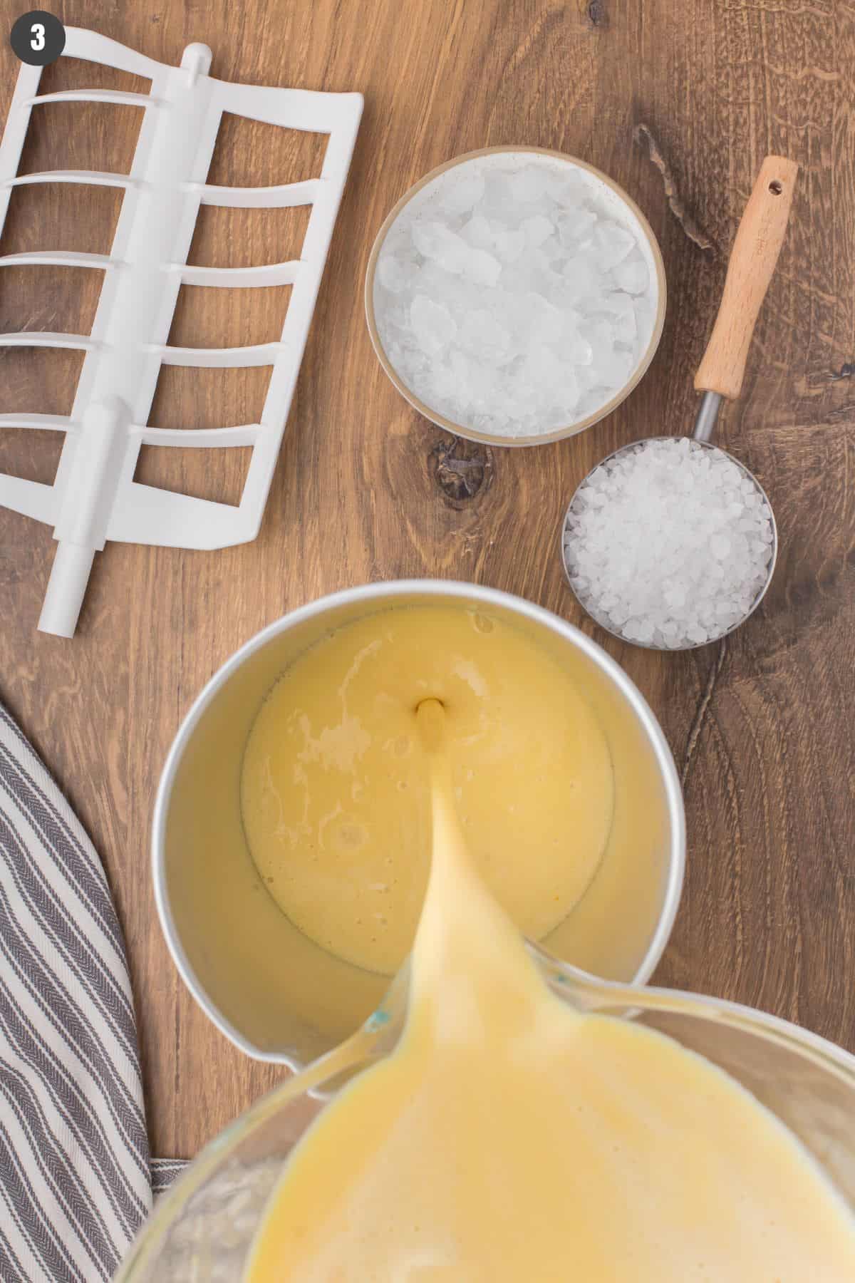 closeup shot showing pouring homemade ice cream mixture into a metal ice cream maker canister