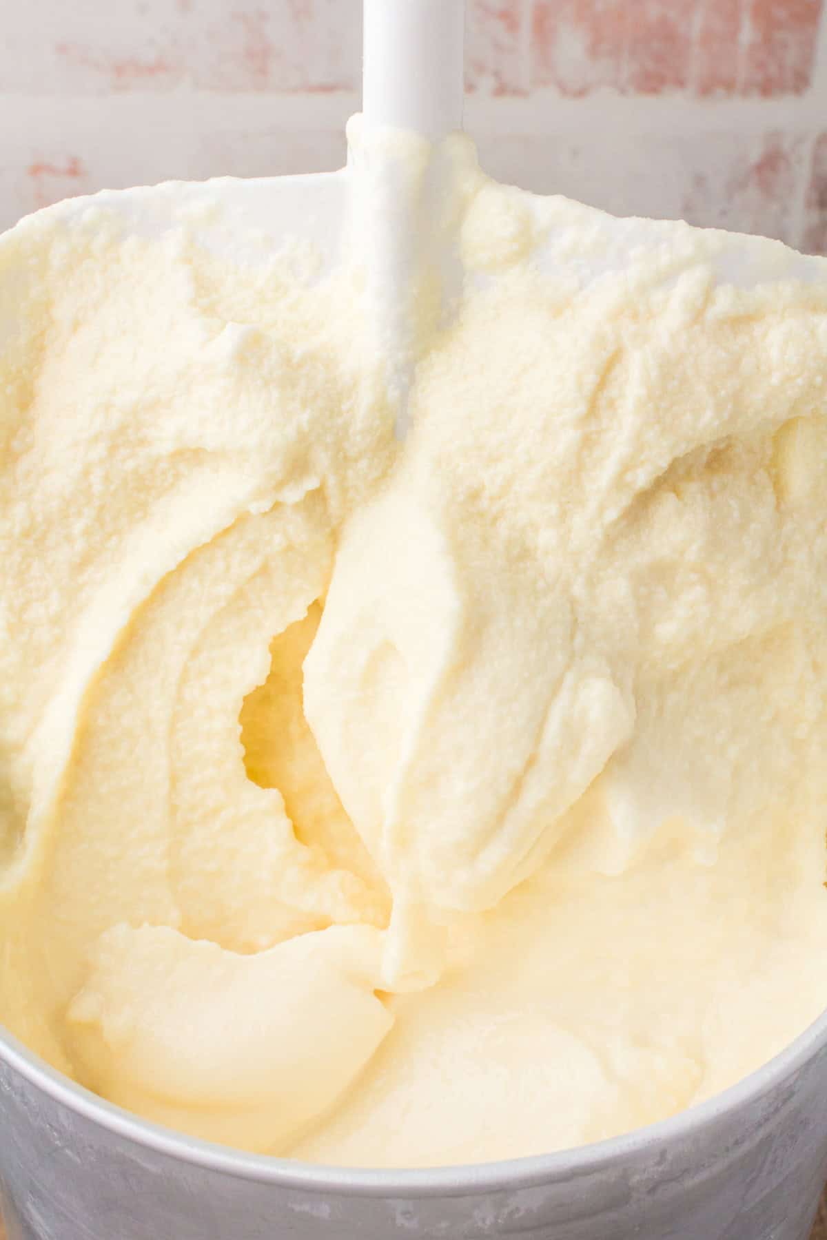 closeup shot showing an ice cream churn full of homemade vanilla ice cream being pulled out of a metal ice cream maker canister