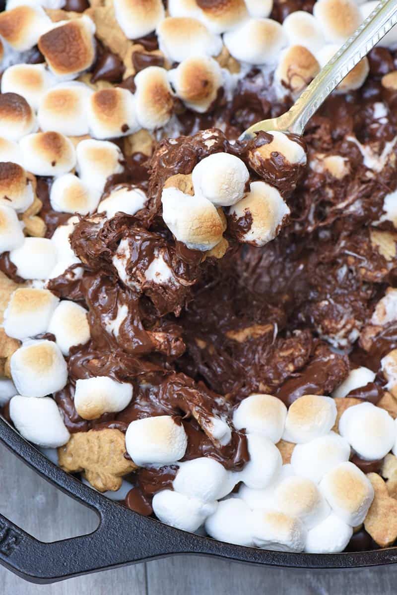 melted chocolate and toasted marshmallows in an easy s'mores dip in cast iron skillet with fork