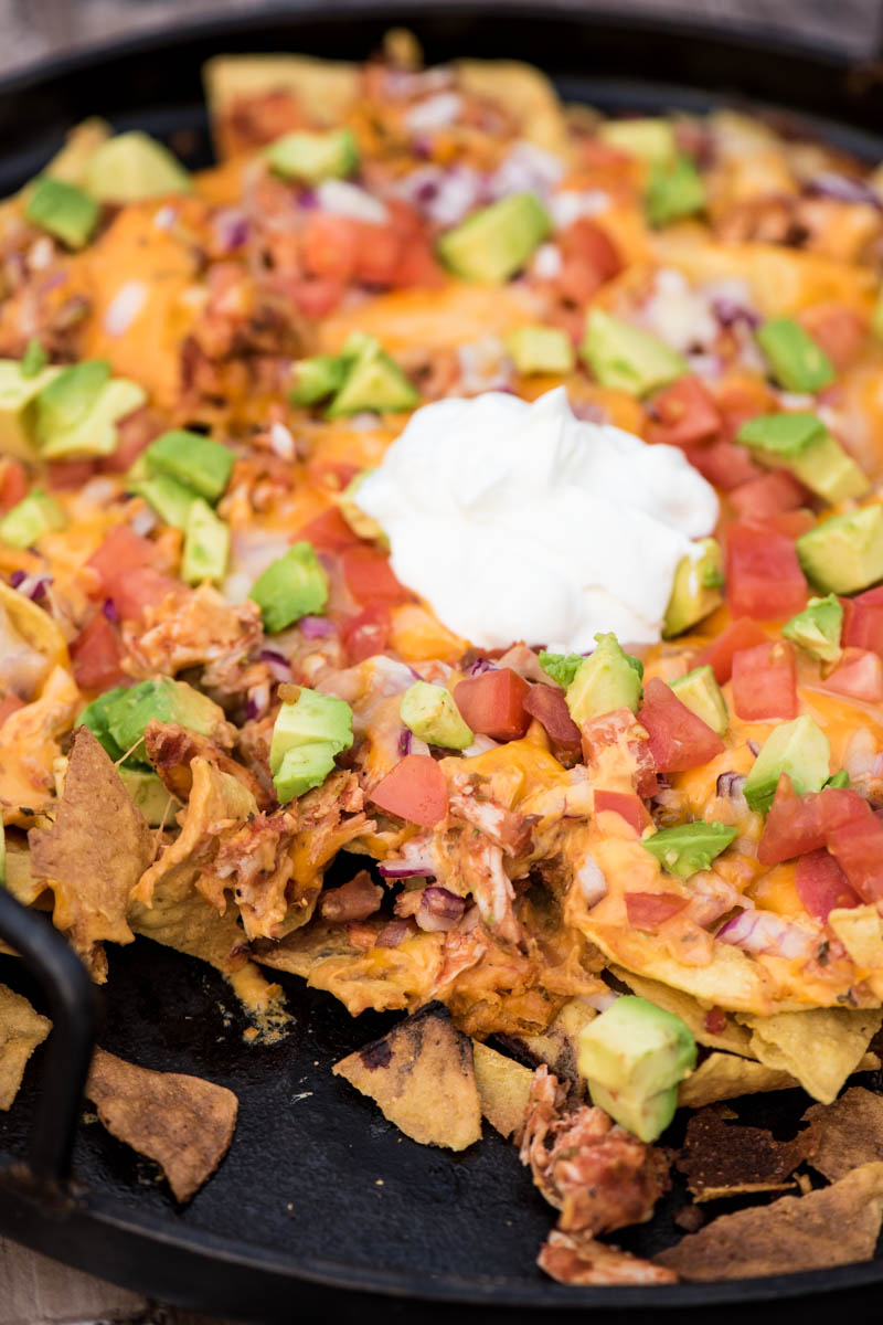 loaded camping nachos with chicken, Roma tomatoes, avocados, and sour cream