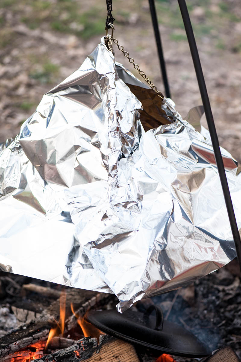 using aluminum foil to act as an oven tent, trapping heat for chicken nachos recipe over the campfire