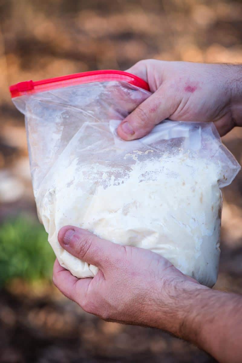 mixing together ingredients for homemade pizza crust over the campfire in Ziploc bag
