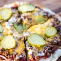 sliced hamburger pizza on a wooden cutting board