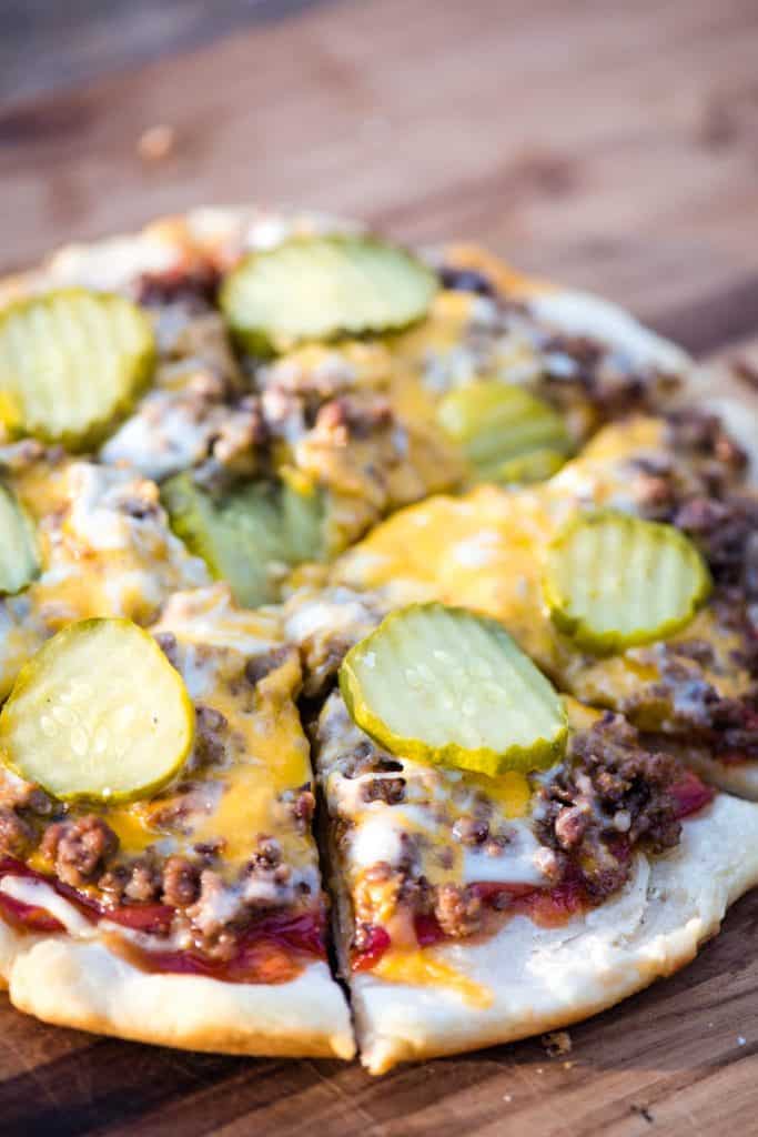 sliced hamburger pizza on a wooden cutting board