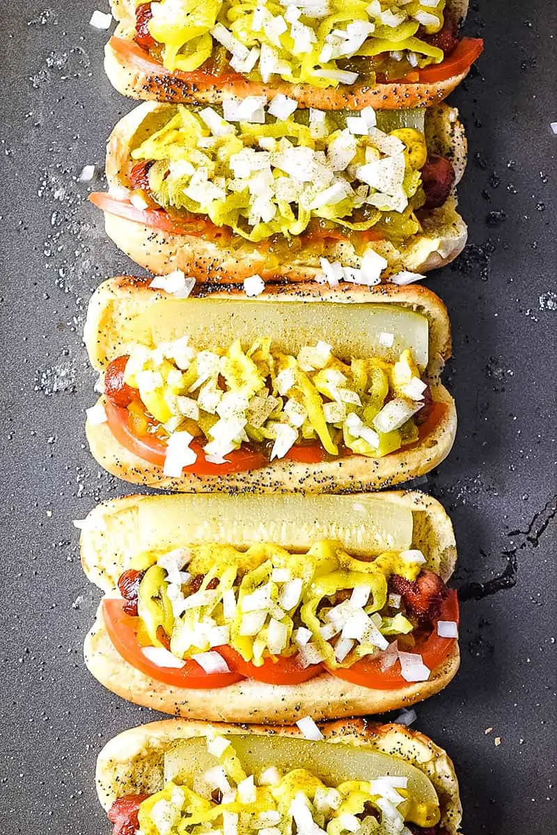 layered Chicago dog in poppy seed buns on baking sheet