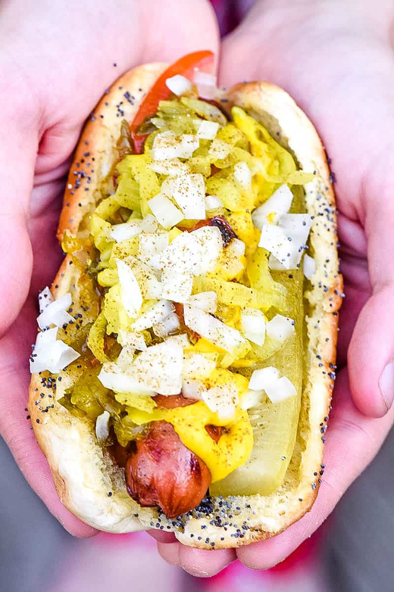 Chicago style hot dog with toppings in hands