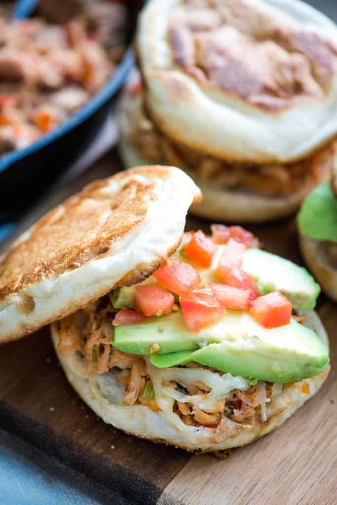 grilled taco tuna melt with avocado on English muffin with tomatoes, on wooden cutting board