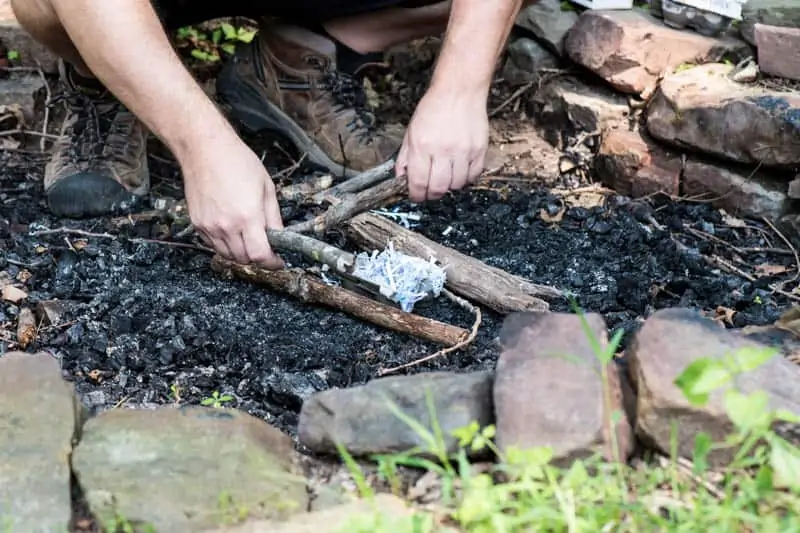 man starting a fire with a homemade fire starter in fire pit
