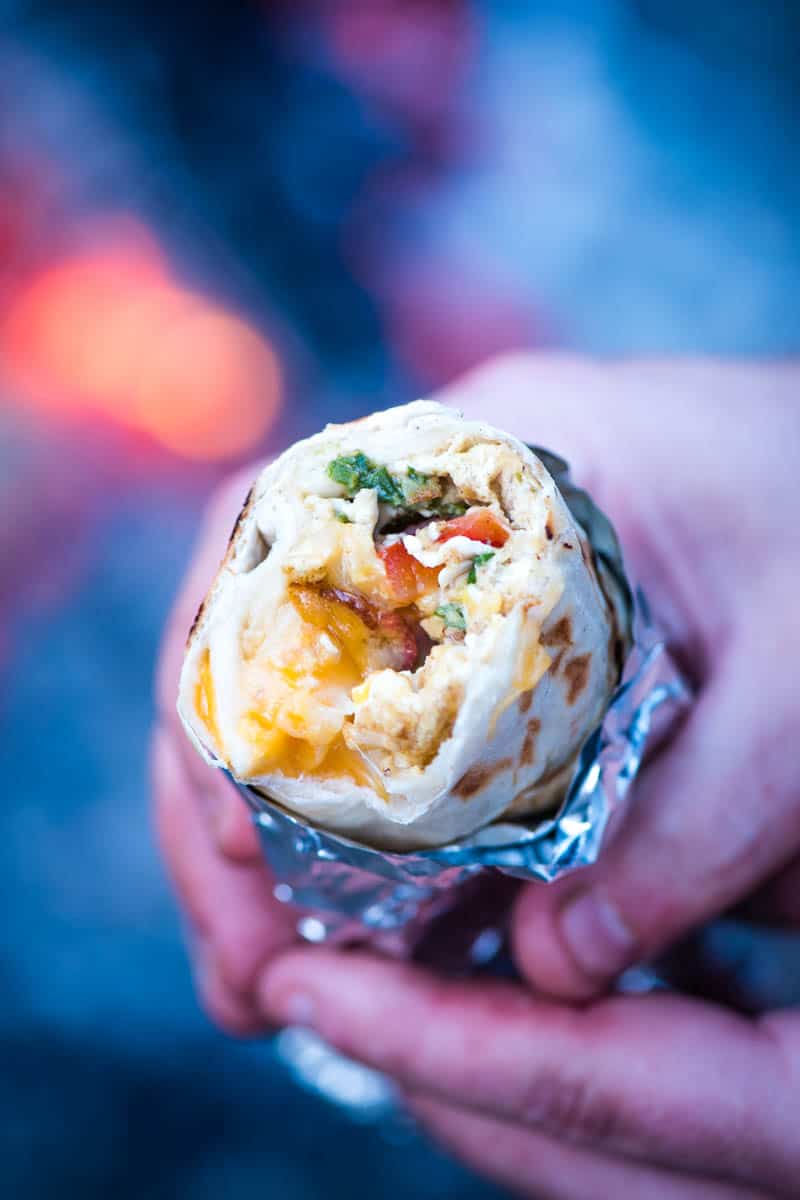 hands holding bacon, egg, and cheese breakfast burrito wrapped in heavy duty foil