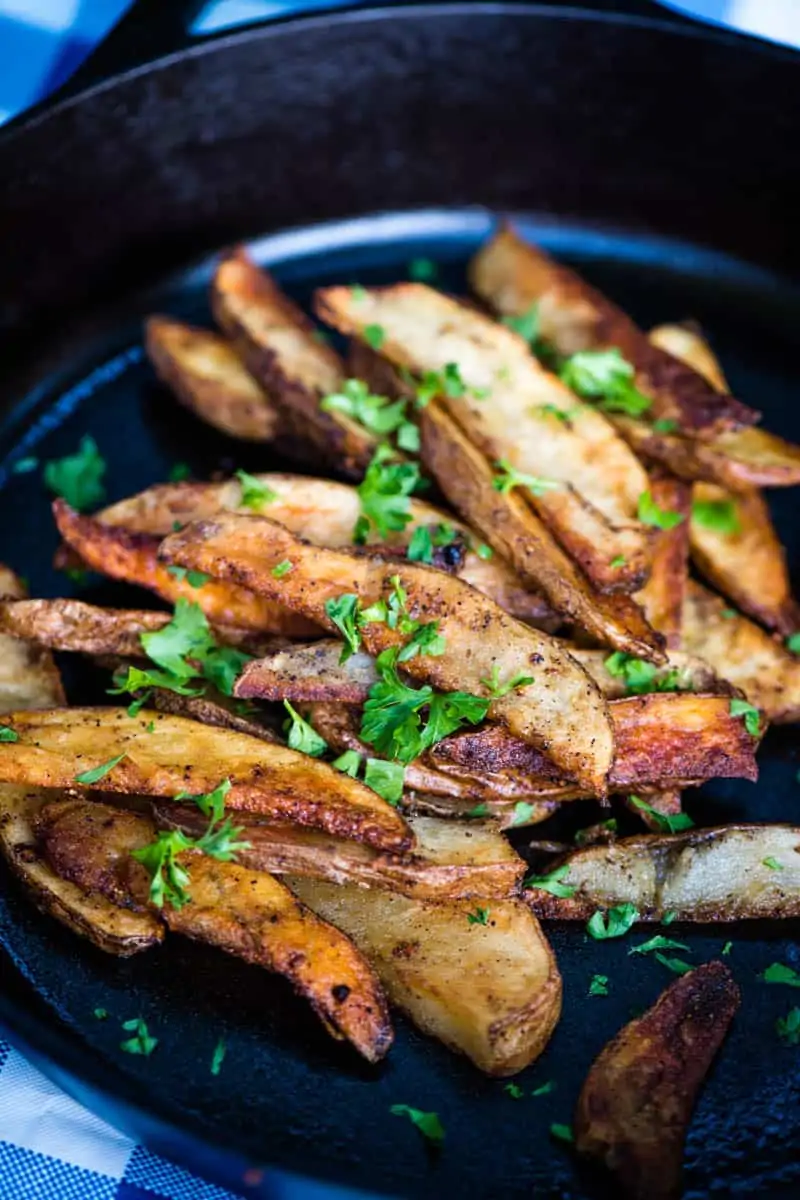 cooked steak fries, sprinkled with chopped parsley, in a cast iron skillet