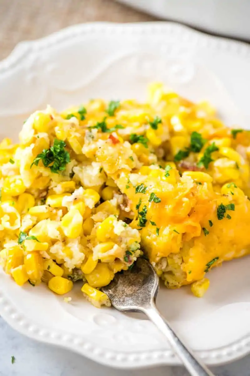 serving of corn casserole with cream cheese on white plate with fork