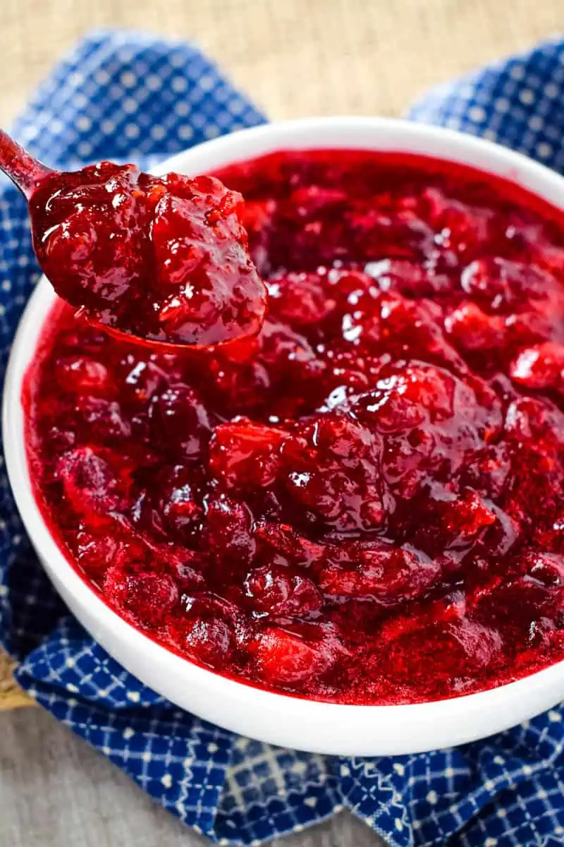 spoonful of homemade cranberry sauce with orange zest in white bowl