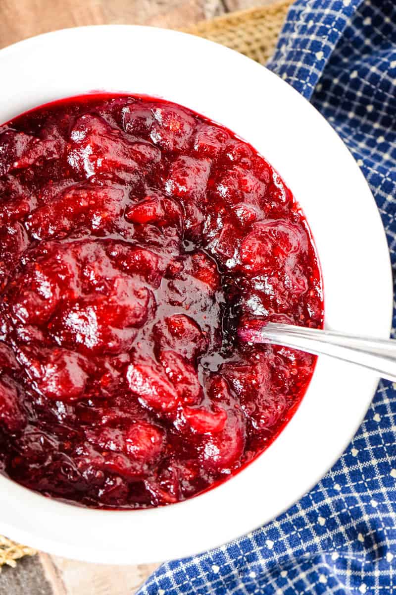 fresh cranberry and orange sauce in white bowl with blue napkin