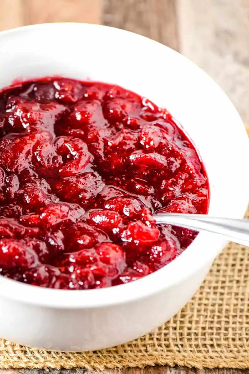 homemade cranberry sauce in white bowl with spoon