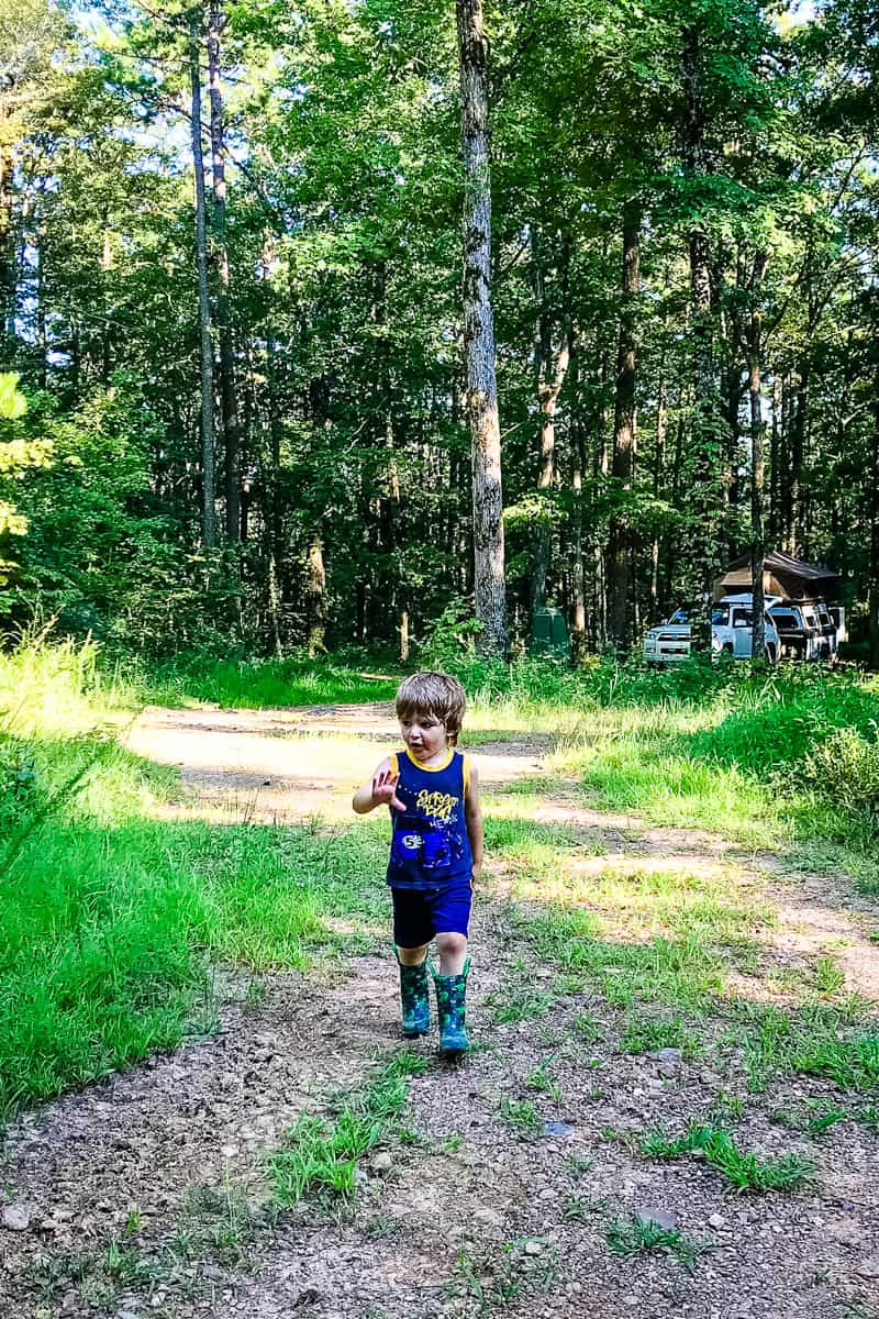 boy walking on road from National Forest camping spot in Arkansas