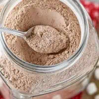 homemade hot chocolate mix in a large glass jar on a red tablecloth