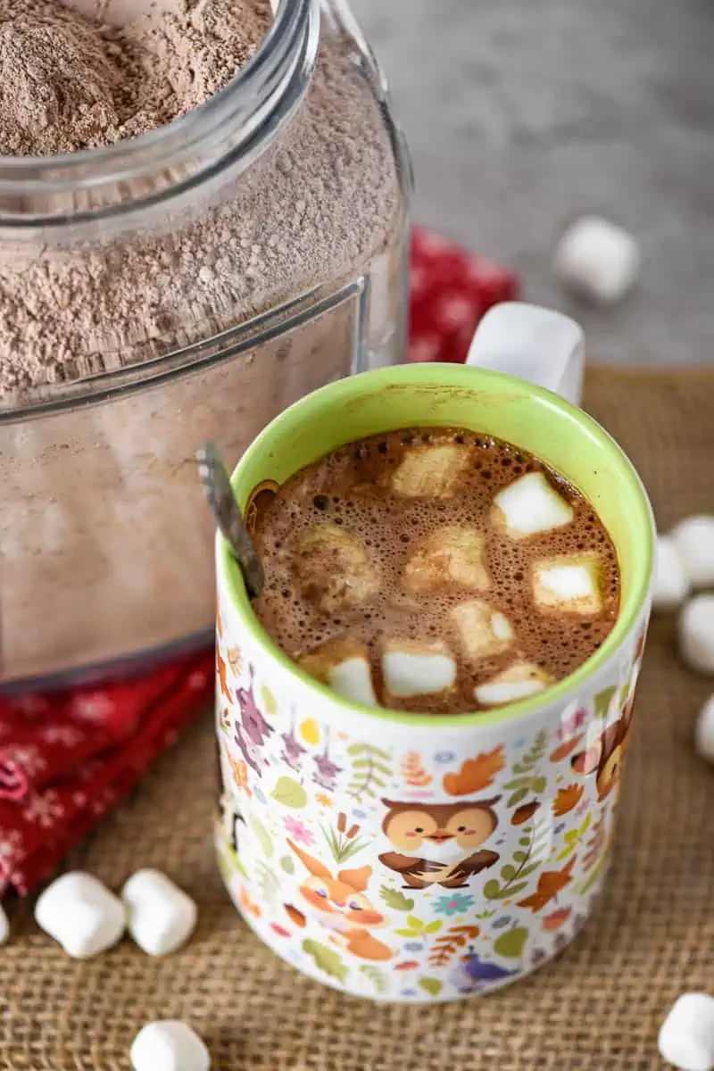 hot cocoa mix made into homemade hot cocoa in mug with spoon and mini marshmallows