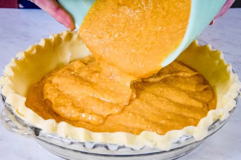 pouring sweet potato pie filling into unbaked pie shell