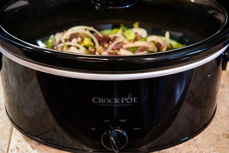 cooking meat for Philly cheesesteaks in black Crock Pot slow cooker on low heat