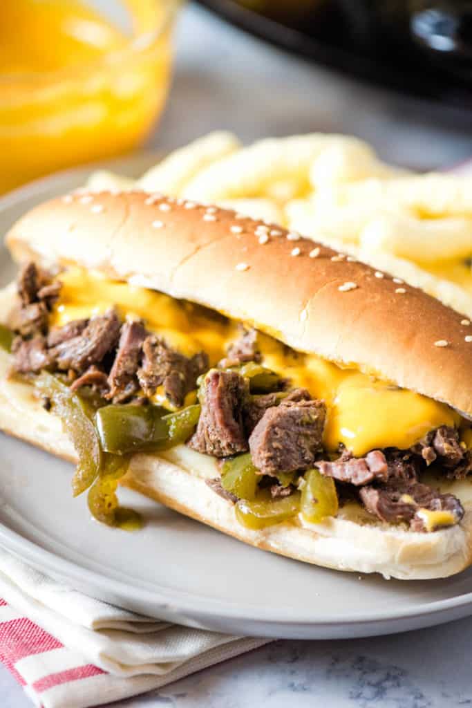 Crock Pot Philly cheesesteak on gray plate with Cheetohs and Cheez Whiz