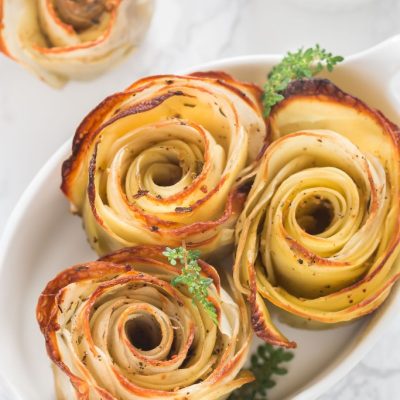 baked potato roses in oval white baking dish on white marble countertop