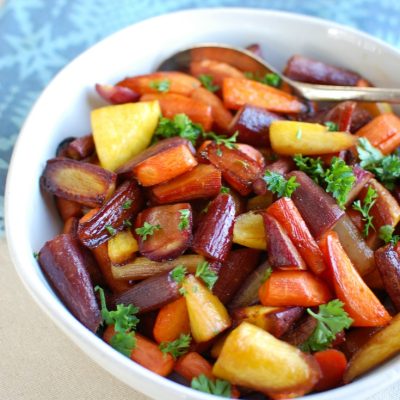 balsamic roasted carrots in white bowl with blue kitchen towel