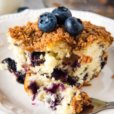 slice of blueberry coffee cake on white plate with fork