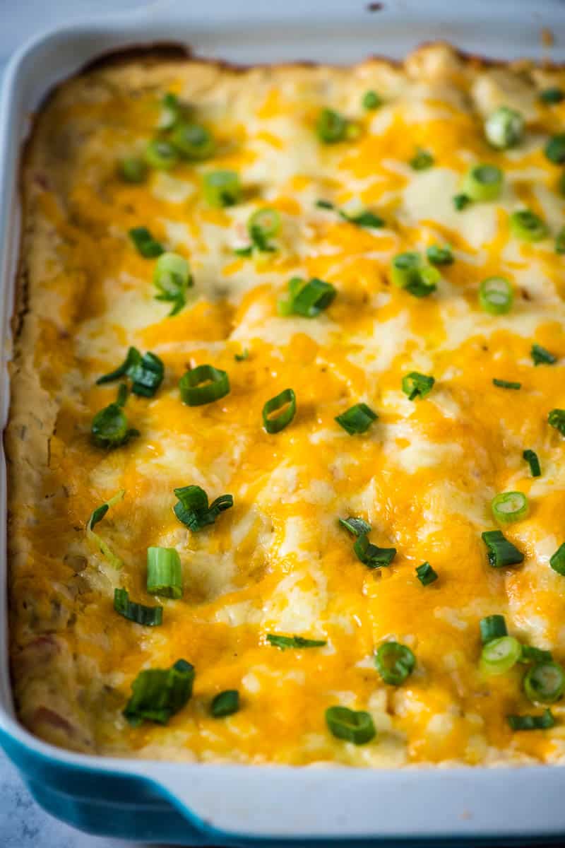 blue baking dish with baked sour cream crab enchiladas, sprinkled with green onions