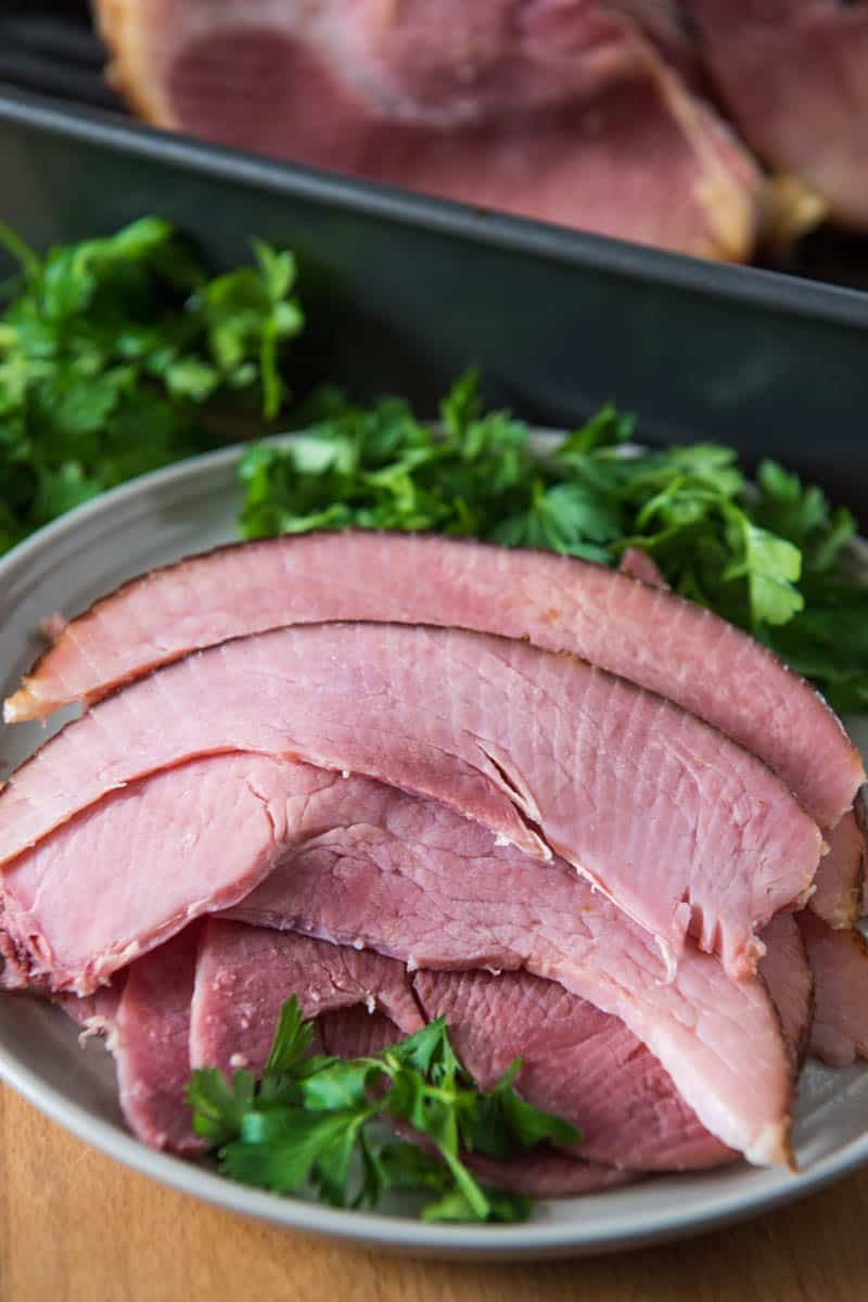 slices of glazed ham on gray plate with Italian parsley