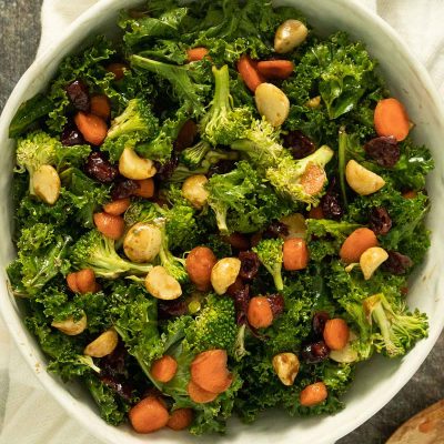 kale and broccoli salad in white bowl on white kitchen towel