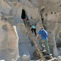 family climbing ladder into cliff home in New Mexico