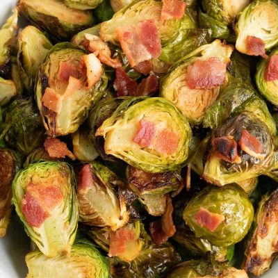 roasted brussels sprouts with bacon in white bowl on wooden countertop