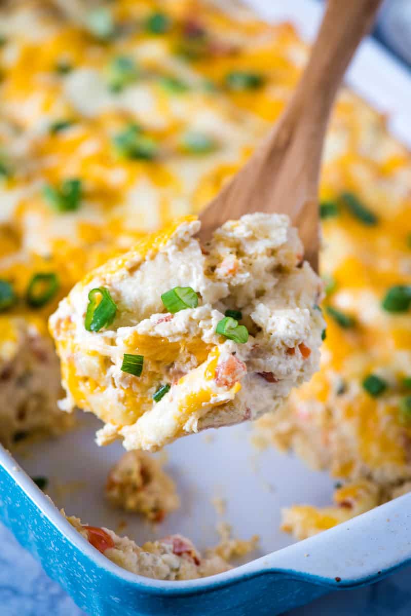 wooden spoonful of sour cream crab enchiladas sprinkled with green onions