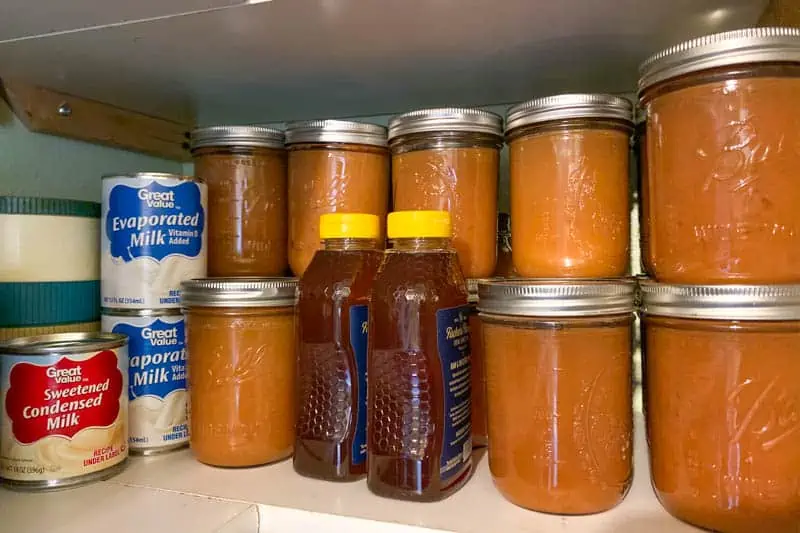 best survival food like home canned applesauce, evaporated milk, and honey on white shelves