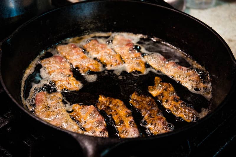frying bacon in cast iron skillet on stovetop