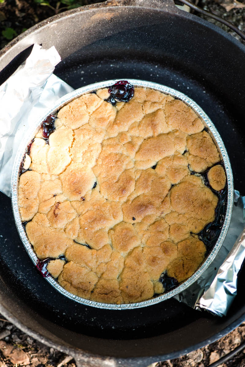 baked sugar cookie cobbler in round foil pan inside cast iron Dutch oven with foil sling