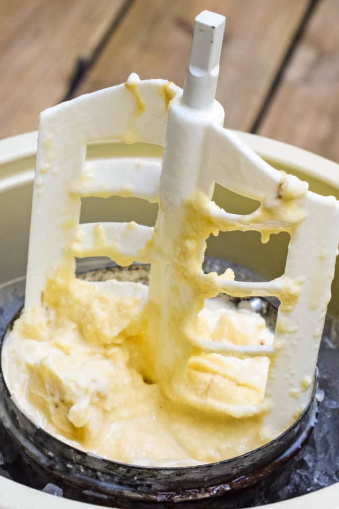 churning paddle pulled up out of metal canister full of homemade banana ice cream