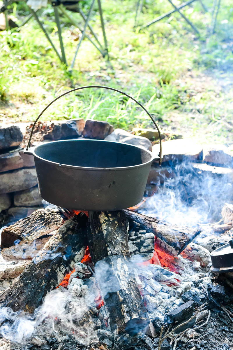 Dutch oven pre-heating over campfire coals
