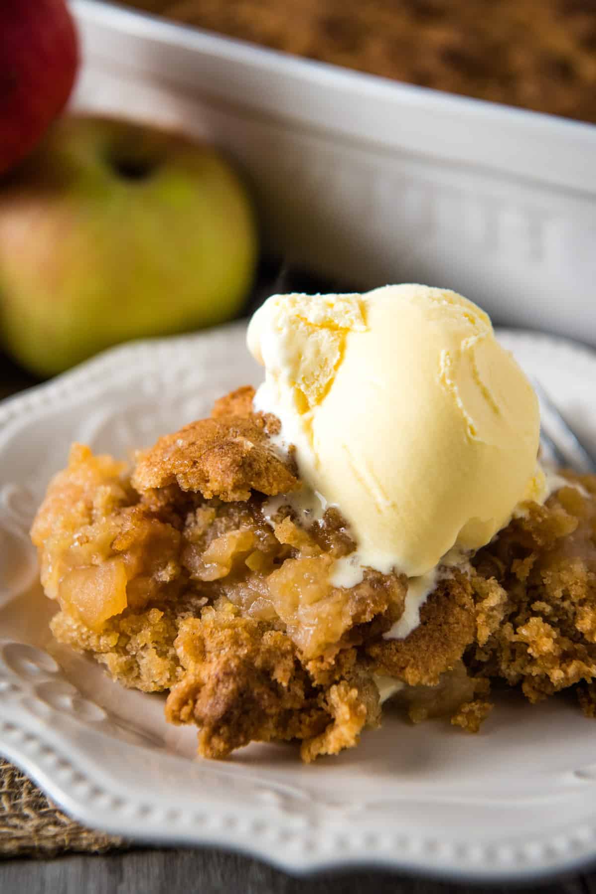 apple crisp without oats served on white plate with vanilla ice cream on top