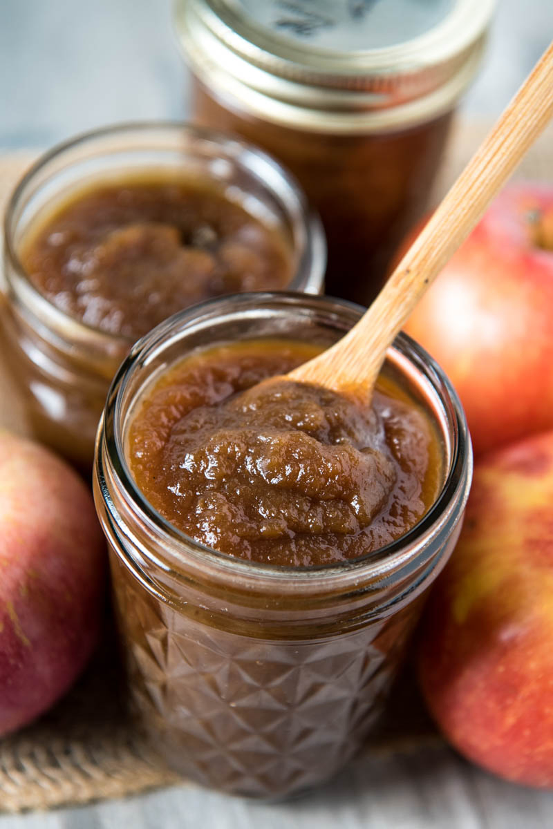 slow cooker apple butter in jelly jar with small wooden spoon