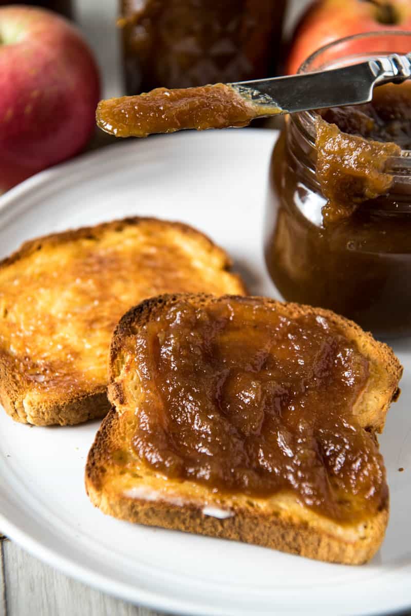 toast on gray plate, spread with easy homemade apple butter, jar of apple butter and butter knife behind toast