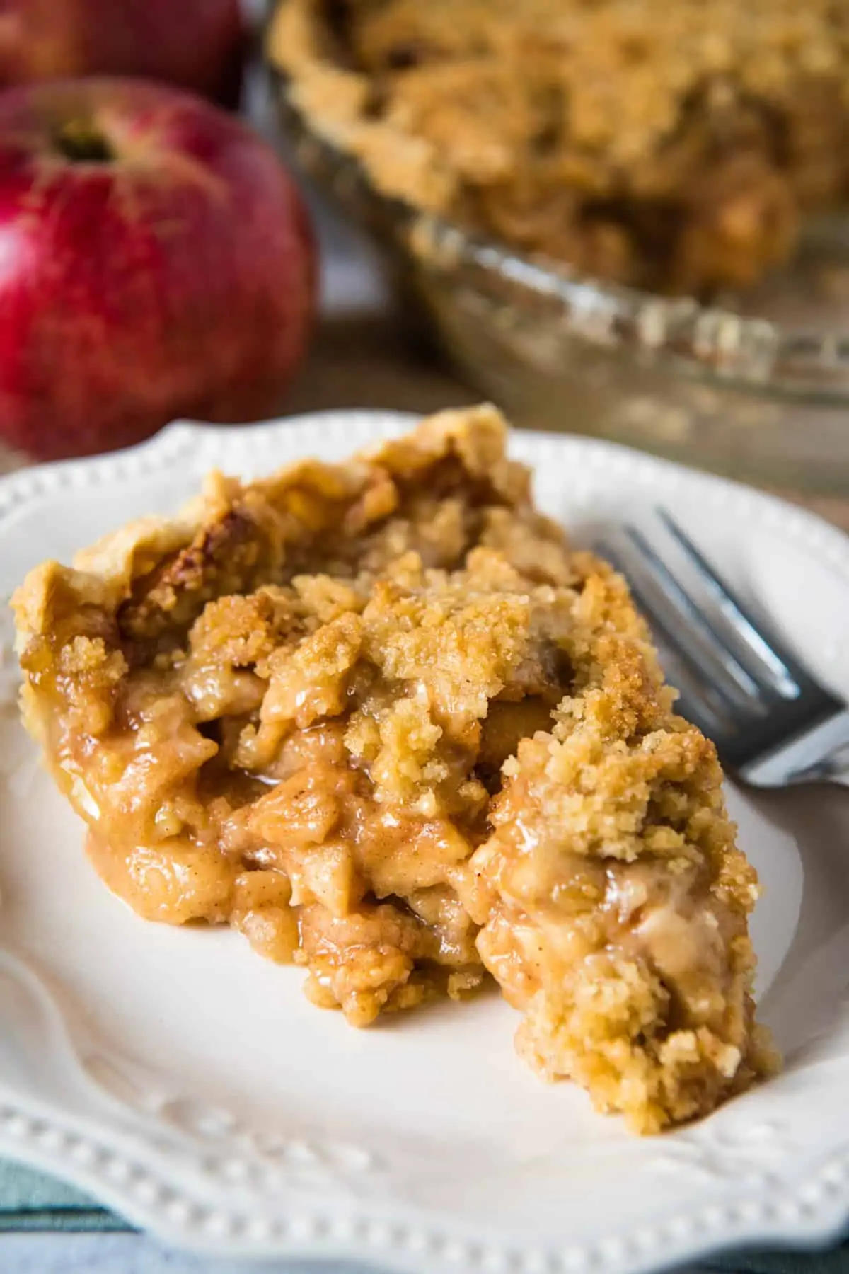slice of apple pie with streusel topping on white plate with fork